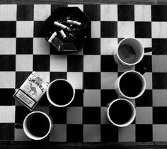 black and white photograph of coffee cups on checkered table