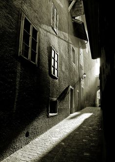 an alley way with brick buildings and windows on both sides, in black and white