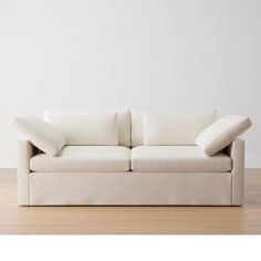 a white couch sitting on top of a hard wood floor next to a white wall