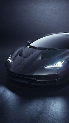 a black sports car is shown in the dark room with its lights on and it's hood up