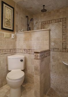 a white toilet sitting inside of a bathroom next to a walk in shower and tiled walls
