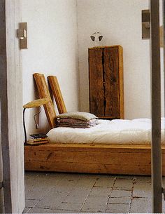 a bed sitting in the middle of a room next to a wooden dresser and mirror