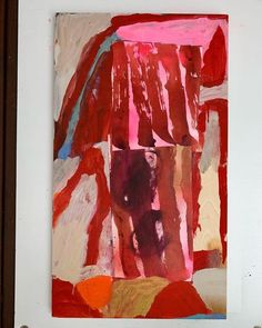 an abstract painting with red, orange and pink colors on white paper in a brown frame