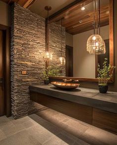 a bathroom with stone walls and lights hanging from it's ceiling, along with a bowl on the counter