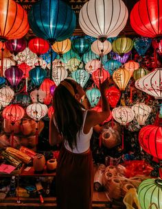 a woman standing in front of many colorful lanterns