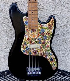 an electric guitar is sitting on top of a wire rack and has a colorful floral design on it