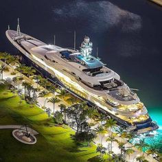 an aerial view of a yacht docked in the water at night with its lights on