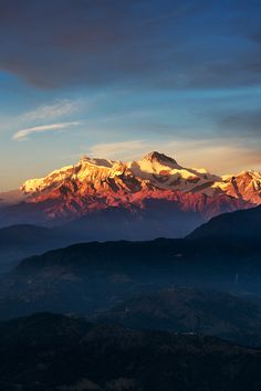 the mountains are covered in snow as the sun is setting over them and there is no image to describe