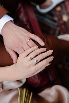 the bride and groom are holding each other's hands while they hold their wedding rings