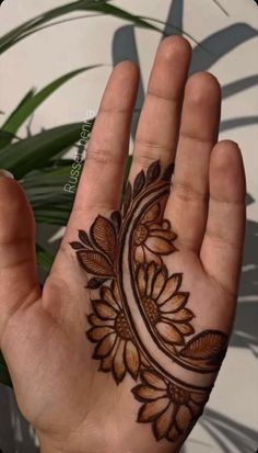 a hand with a henna tattoo on it's palm and leaves in the background