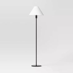 a black floor lamp with a white shade on the top and one light on the bottom