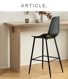 a black bar stool sitting in front of a white brick wall