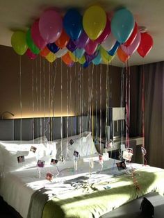 balloons floating from the ceiling over a bed in a hotel room with a large window