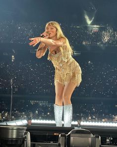 the singer is performing on stage with her legs spread out in front of an audience