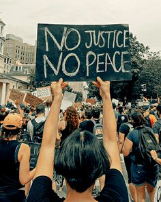 people holding up signs in the middle of a street with no justice and no peace written on them