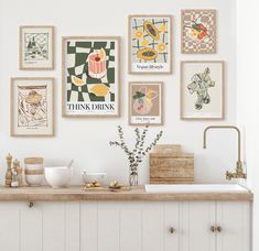 there are many framed pictures on the wall above the kitchen counter and below the sink