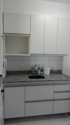 a kitchen with white cabinets and gray counter tops