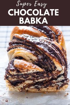 a pastry with chocolate and powdered sugar swirls on it's side, sitting on top of wax paper