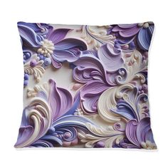 a decorative pillow with purple and white flowers on the front, sitting on a white surface