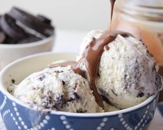 a scoop of ice cream being drizzled with chocolate on top in a blue bowl