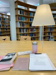 a lamp and some books on a table in a room full of bookshelves