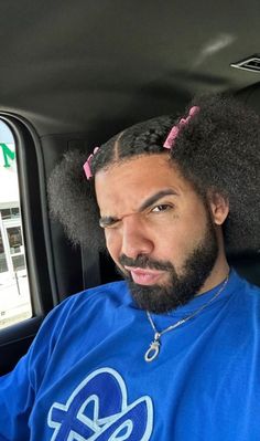 a man sitting in the back seat of a car with an afro on his head