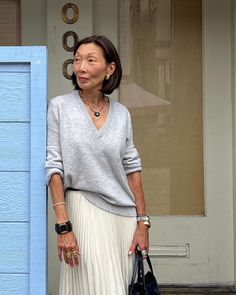 an older woman standing in front of a blue door with her hand on her hip