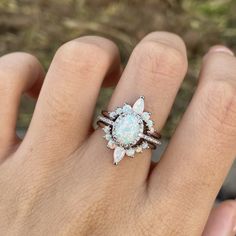 a woman's hand holding a ring with an opalite and diamond center