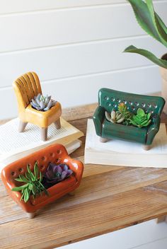 three ceramic planters sitting on top of a wooden table next to an open book