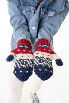a pair of knitted mittens sitting on top of someone's legs