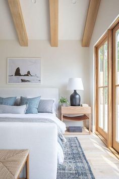 a bedroom with white walls and wooden beams