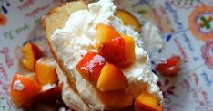 a piece of cake with peaches and whipped cream on top sits on a colorful plate