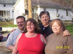 three people standing next to each other in front of a house