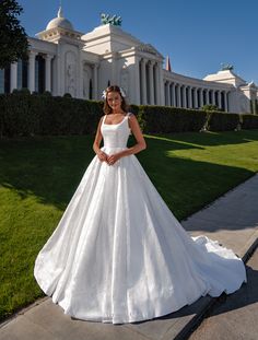 a woman in a white wedding dress standing on the sidewalk near a building with columns
