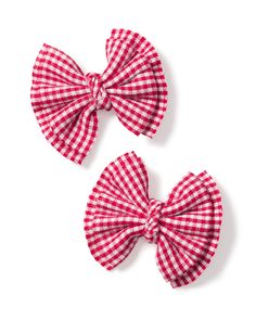 two red and white gingham bows are on a white surface, one is in the shape of a bow