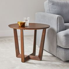 a wooden table with a glass on it in front of a gray couch and chair