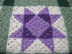 a purple and white crocheted star on a blanket