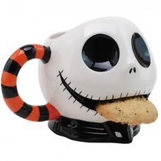 a ceramic mug with a cookie in it's mouth and a skeleton face on top