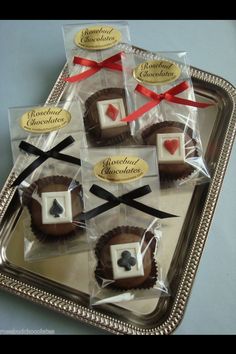 some chocolates are wrapped in cellophane and tied with red ribbon on a silver tray