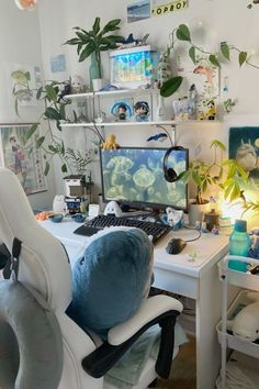 a computer desk with two monitors on top of it and plants growing in the background