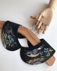 a hand holding a wooden object next to two pieces of fabric with birds on them