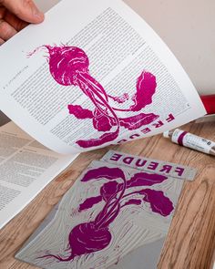 an open book on a wooden table with paper and crayon markers next to it