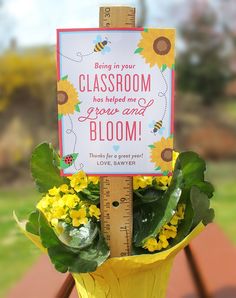 a yellow vase filled with flowers next to a ruler on top of a wooden table