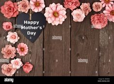 pink flowers are arranged in the shape of a heart on a wooden background with a happy mother's day sign