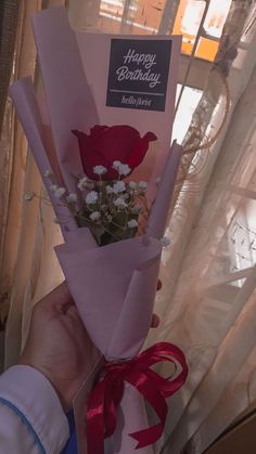 a person holding a bouquet of flowers in their hand with a happy birthday card on it