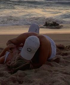 a woman laying on top of a sandy beach next to the ocean