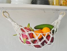 there is a fruit basket hanging on the shelf with other fruits and vegetables in it