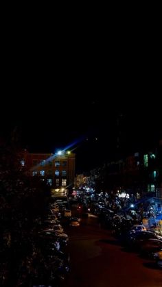 a city street at night with lots of cars parked on the side of the road