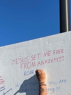 a person writing on a white wall with blue sky in the background