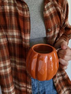 a person holding a pumpkin shaped vase in their hands